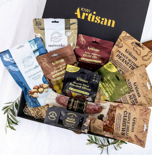 Assorted gourmet snacks in a 'Kiwi Artisan' box on a white background