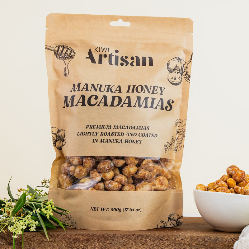Bag of Kiwi Artisan Manuka Honey Macadamias on a wooden surface with a bowl of macadamias.