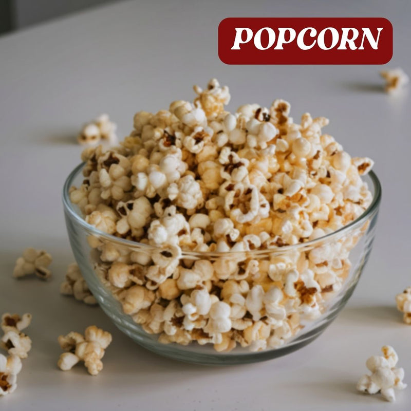 Clear glass bowl filled with popcorn on a light surface, with 'POPCORN' text at the top.