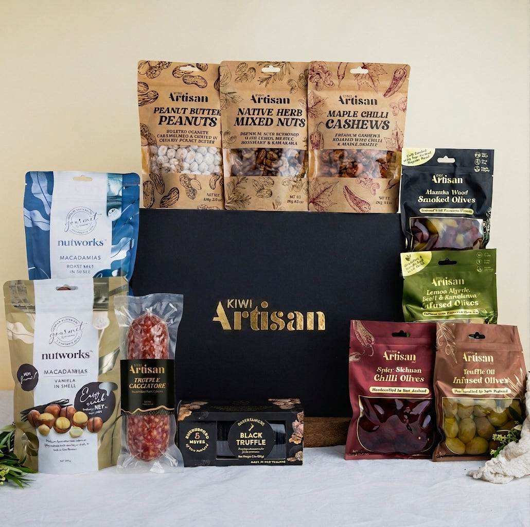 Assorted gourmet food items including nuts, olives, and truffles displayed in front of a Kiwi Artisan box.