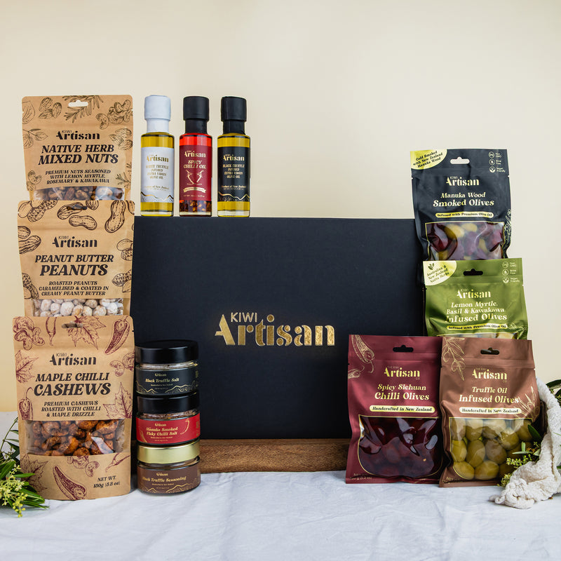 Kiwi Artisan Gift Box containing food products including nuts, truffle oils, seasonings and olives on a white surface.