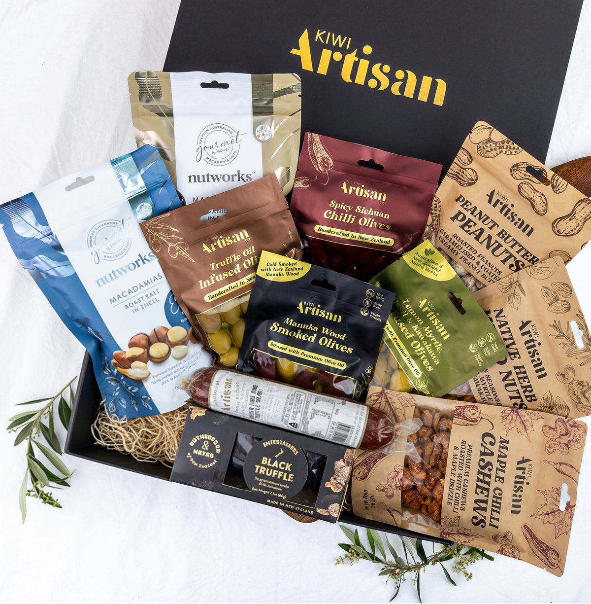 Assorted food items in a 'Kiwi Artisan' box on a white background