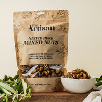 Kiwi Artisan Native Herb Mixed Nuts packaging with a bowl of nuts on a wooden surface.