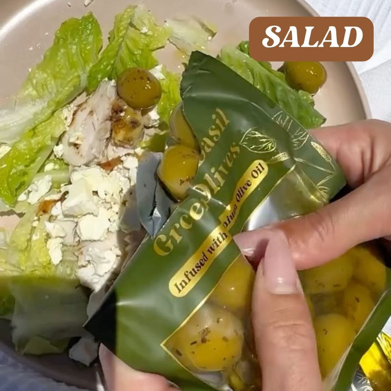 Hand holding a package of Ercolinas olive oil over a salad with lettuce and olives.
