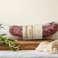 Packaged salami with a label on a wooden board