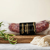 Packaged truffle  salami with 'Artisan' label on a wooden board with decorative elements.